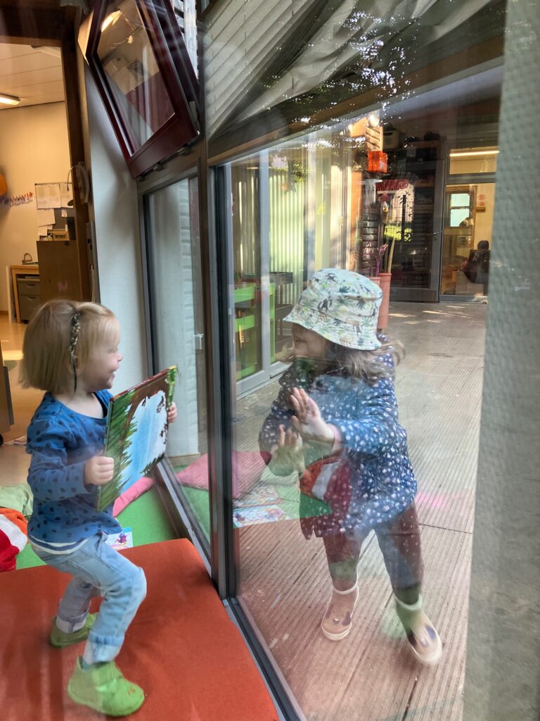 Kinder beobachten sich durch Fensterscheibe