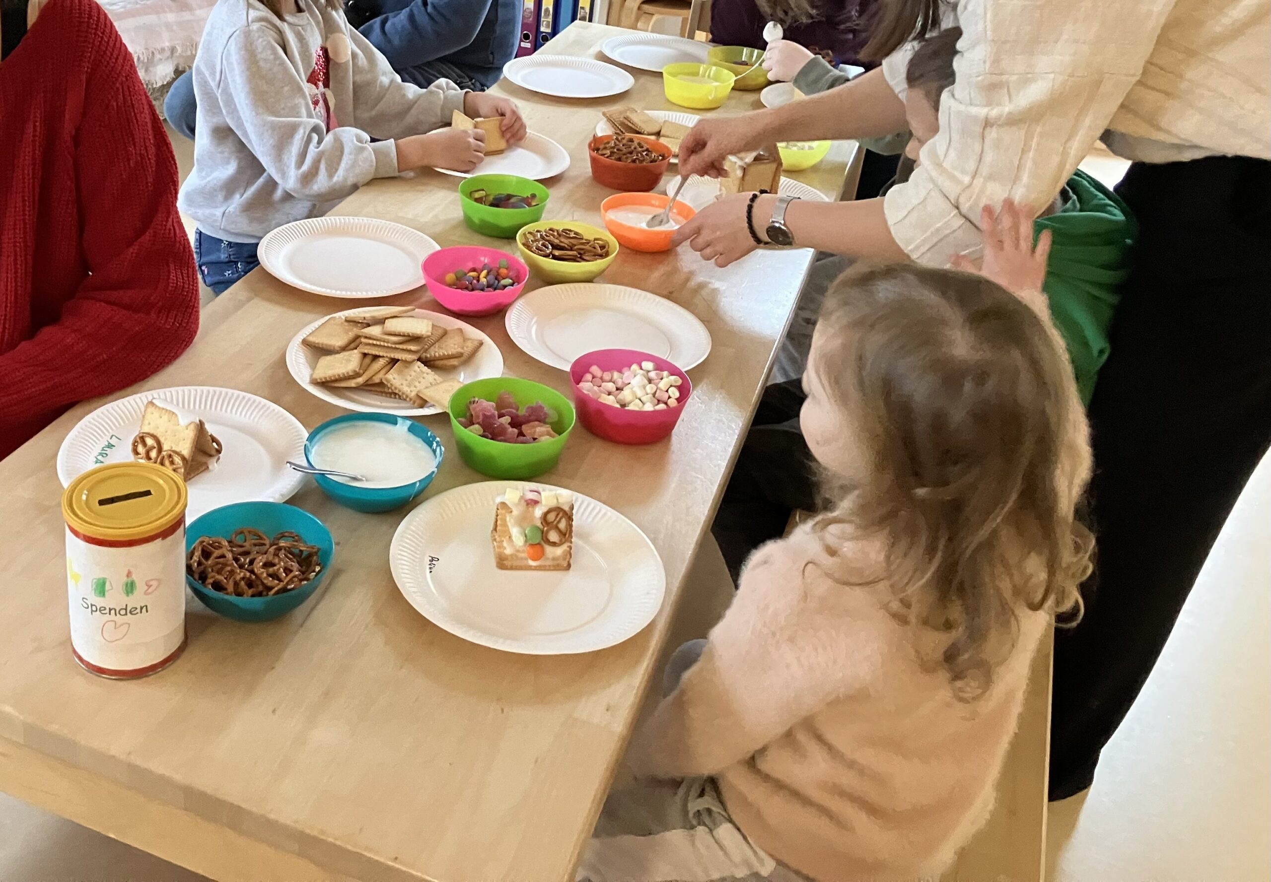 Kinder werden beim Kekshausbasteln unterstützt