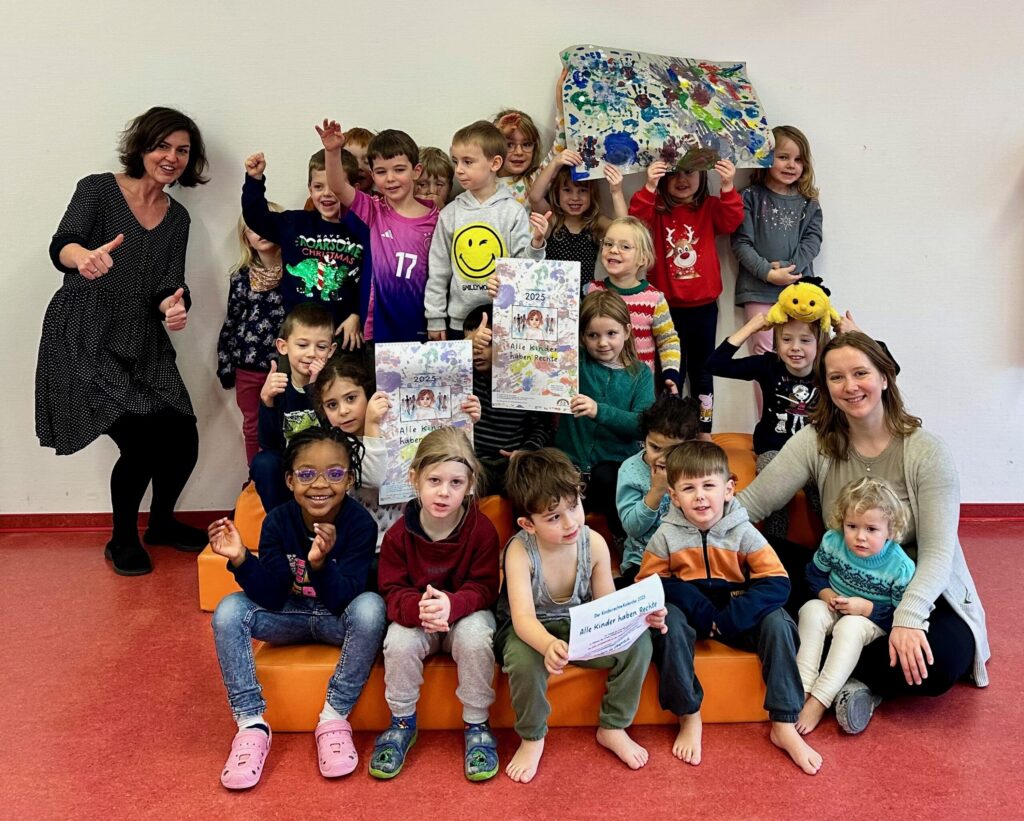 Gruppe von Kindern und Erzieher präsentieren den Kinderrechte-Kalender