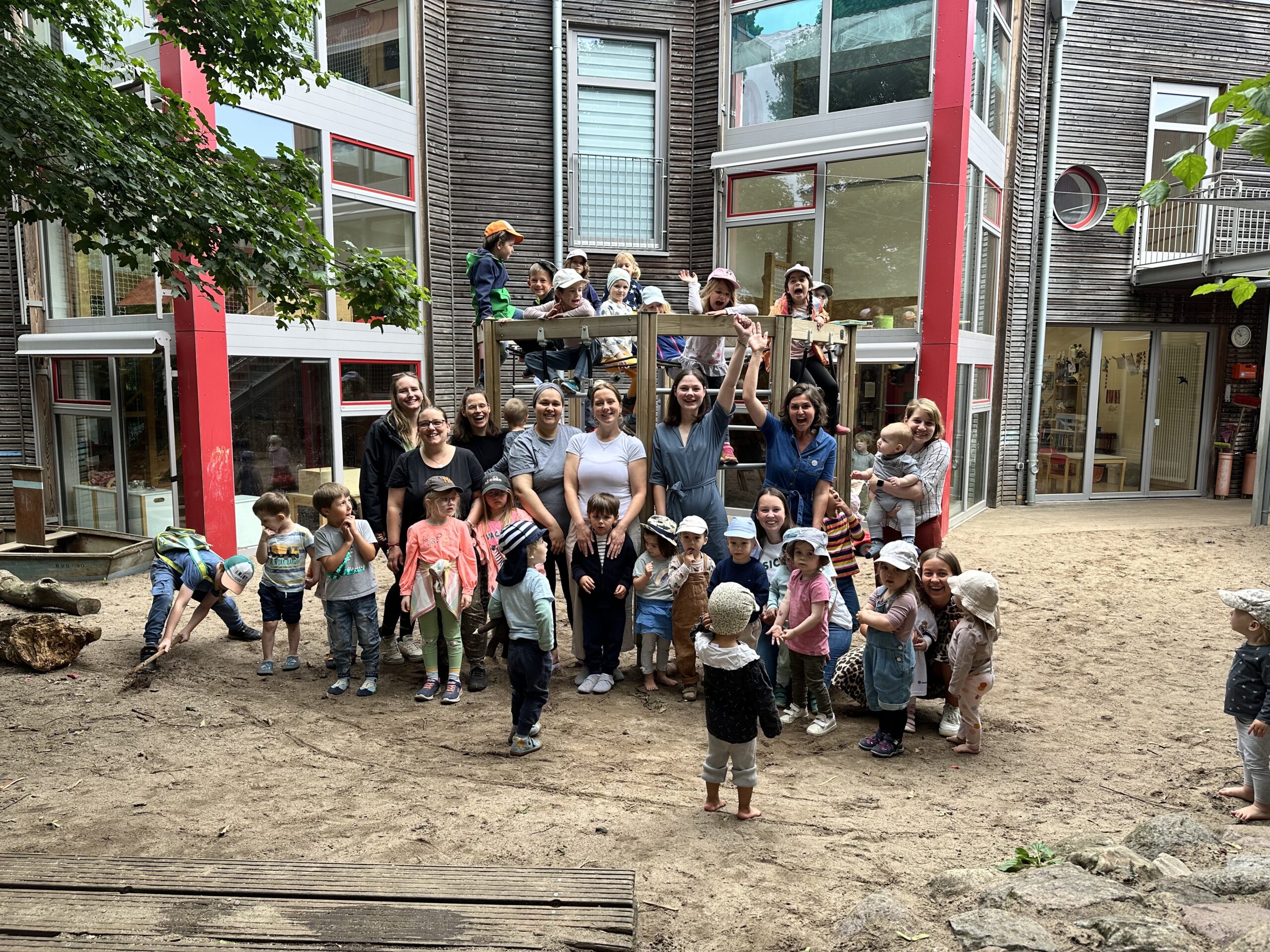Gruppenfoto von jubelnden Kindern und Fachkräften vor Klettergerüst