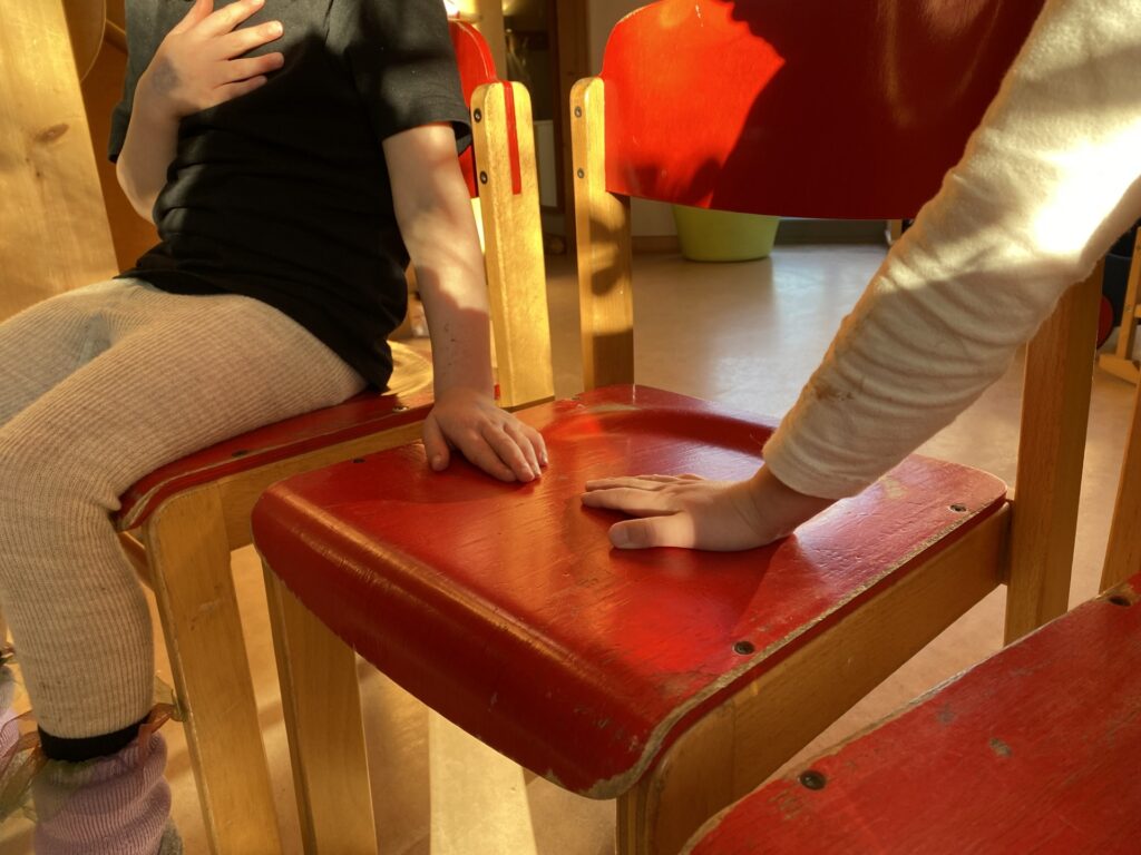 Kinderhände auf Stuhlsitzfläche